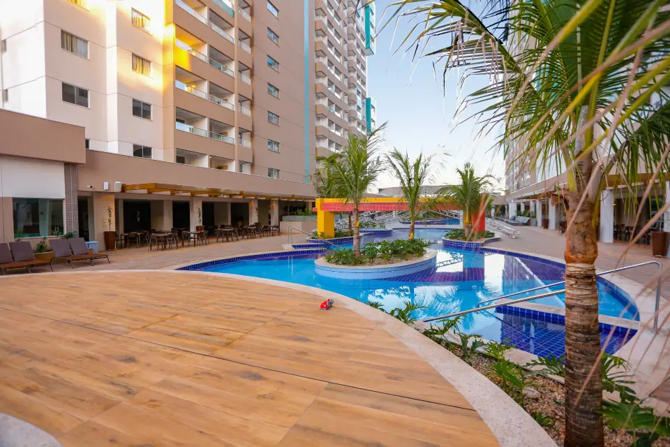 Piscina do Enjoy Olímpia Park Resort cercada por palmeiras e deck de madeira